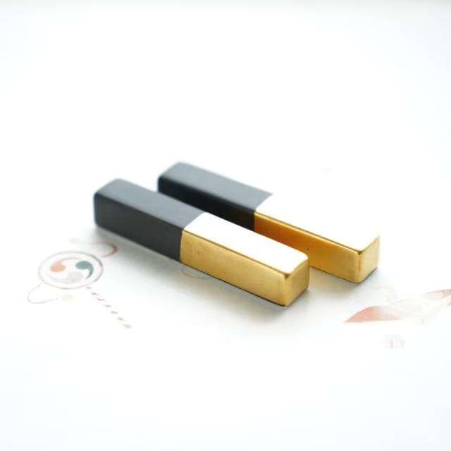 Two matte black and gold porcelain rests side by side